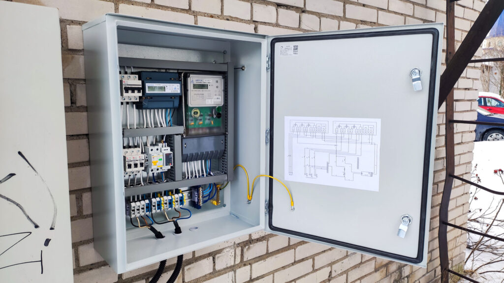 Открытый электрический щит с автоматами, счётчиком и схемой при проверке электрики дома