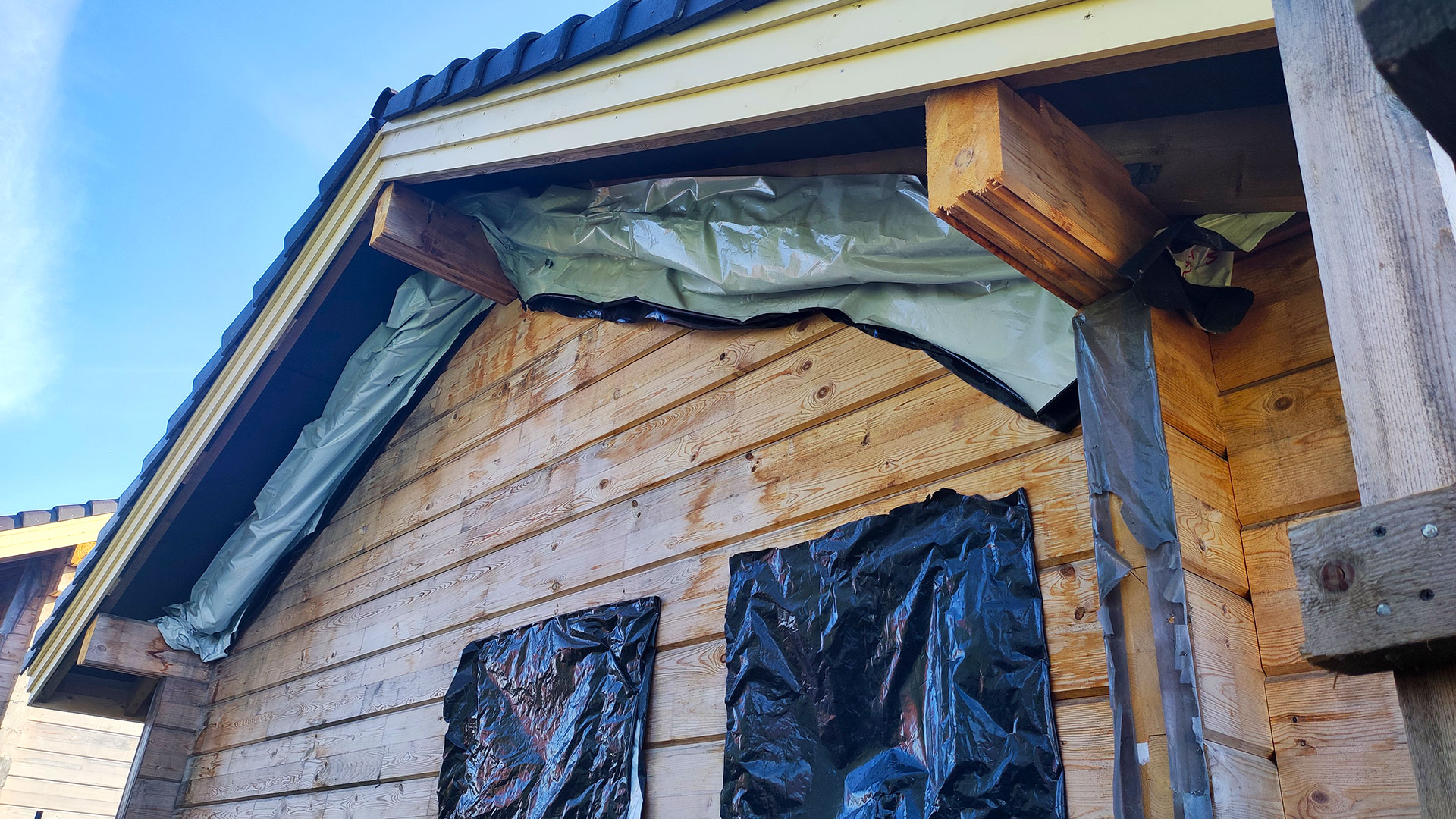 Намокание деревянной стены под кровлей и вскрытый узел примыкания при обследовании причины увлажнения