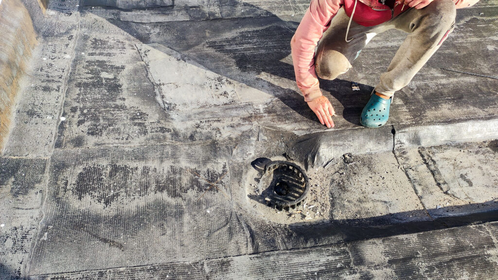 Осмотр водосточной воронки на мягкой кровле при поиске причины протечки