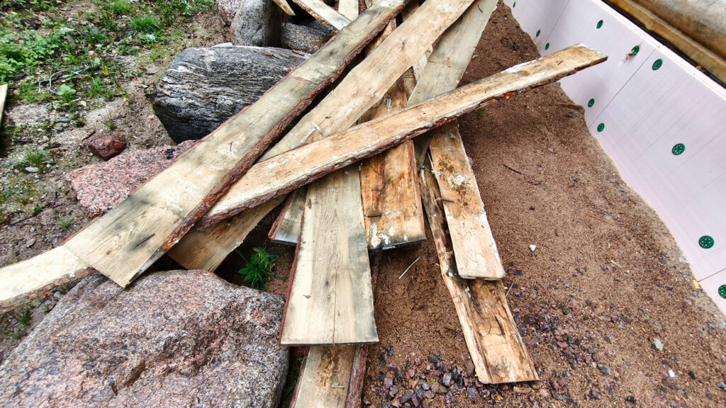 Доски лежат на земле без нормального хранения и защиты от влаги на строительной площадке