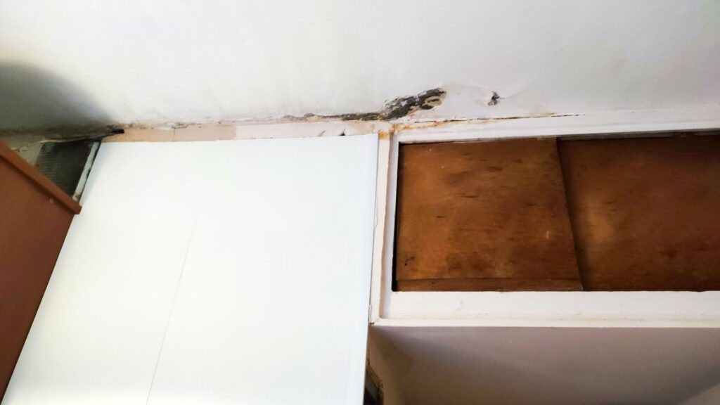 Следы протечки и плесени у потолка над шкафом в верхней части помещения