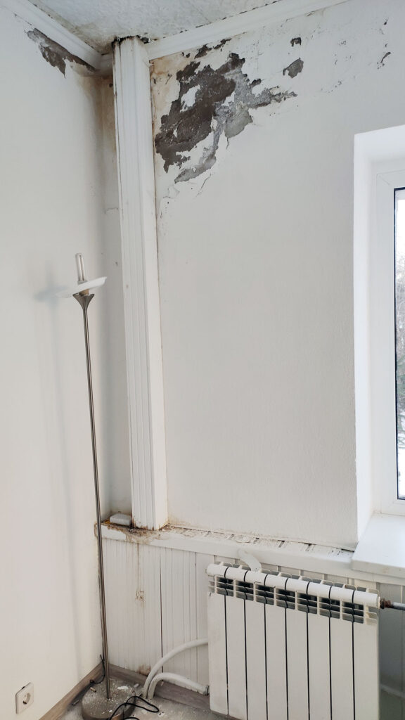 Следы залива на стене возле окна и стояка в комнате