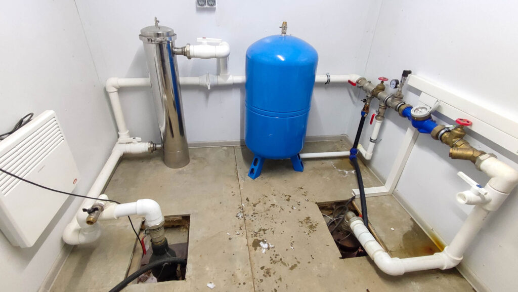 Узел водоснабжения с гидроаккумулятором, фильтром и арматурой в частном доме при осмотре перед приёмкой