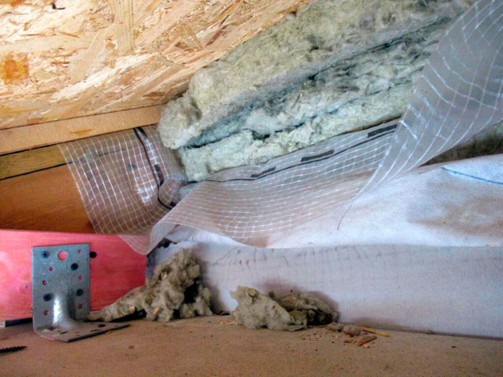 Вскрытый кровельный узел с утеплителем и пароизоляцией при обследовании причины намокания стен